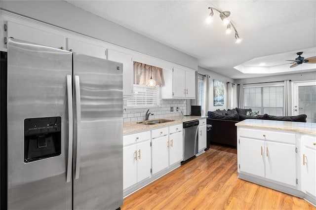 kitchen featuring sink, light hardwood / wood-style flooring, decorative backsplash, appliances with stainless steel finishes, and white cabinetry