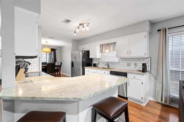 kitchen with kitchen peninsula, plenty of natural light, white cabinets, and stainless steel appliances