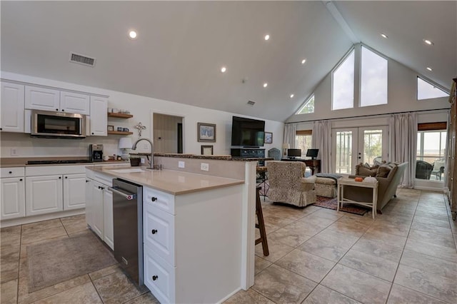 kitchen with sink, white cabinetry, stainless steel appliances, high vaulted ceiling, and a kitchen island with sink