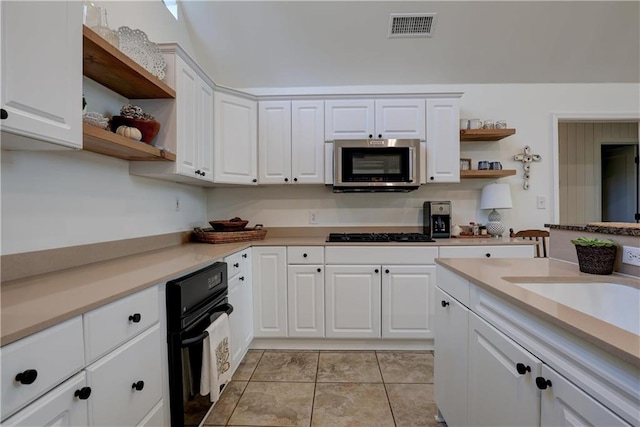 kitchen with light tile patterned flooring, white cabinetry, and black appliances