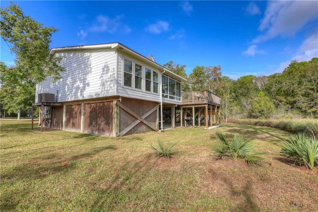 rear view of house featuring a wooden deck and a yard