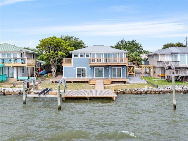 back of property with a water view and a balcony