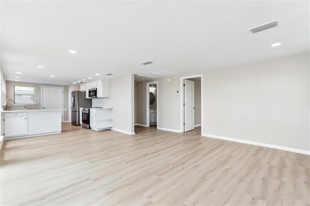 unfurnished living room with sink and light wood-type flooring