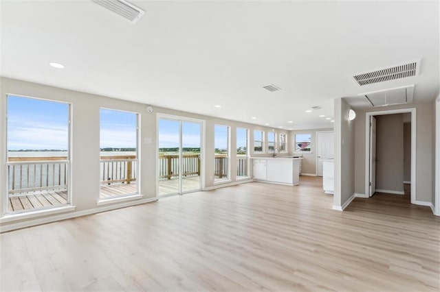 unfurnished living room featuring a water view and light hardwood / wood-style flooring