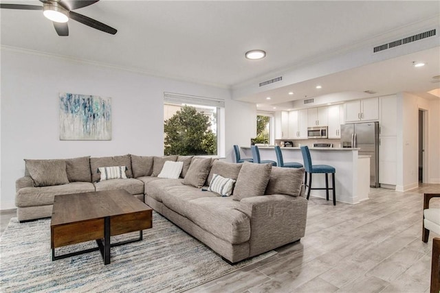 living room with ornamental molding, light hardwood / wood-style flooring, and ceiling fan