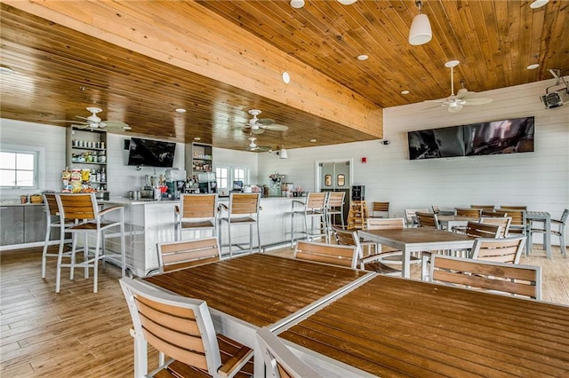 dining space with wood ceiling, wood walls, bar area, and light wood-type flooring