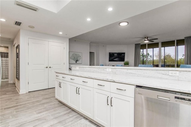 kitchen with light hardwood / wood-style floors, white cabinetry, stainless steel dishwasher, and light stone counters