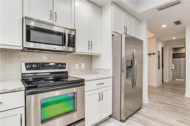 612 Lost Key Dr Unit 205B, Pensacola, FL 32507 - kitchen with stainless steel appliances, baseboards, white cabinetry, light wood-type flooring, and decorative backsplash