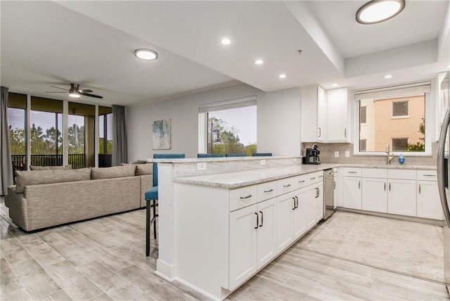 kitchen featuring kitchen peninsula, white cabinetry, plenty of natural light, and light wood-type flooring