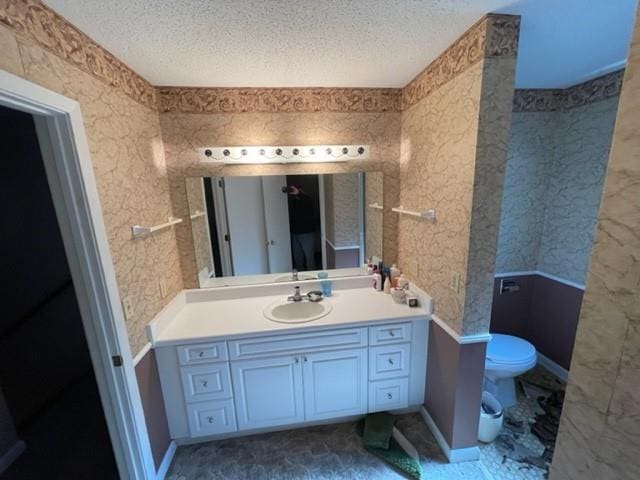 bathroom with vanity, a textured ceiling, and toilet