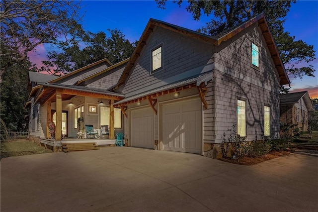 exterior space featuring driveway, covered porch, and a garage