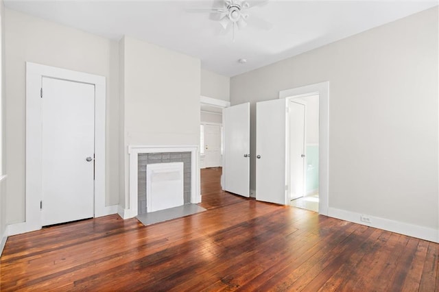 unfurnished living room featuring dark hardwood / wood-style floors, a tiled fireplace, and ceiling fan