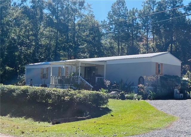 manufactured / mobile home featuring covered porch and a front lawn