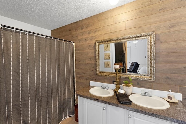 bathroom with vanity, a textured ceiling, and wooden walls