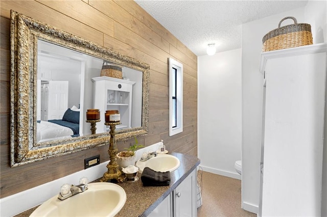 bathroom featuring vanity, wooden walls, a textured ceiling, and toilet