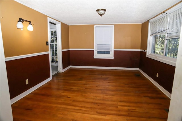 empty room with dark wood finished floors, a textured ceiling, and baseboards