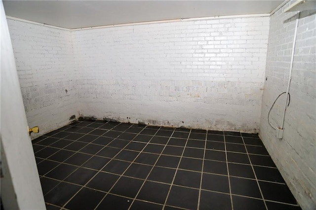 unfurnished room featuring brick wall