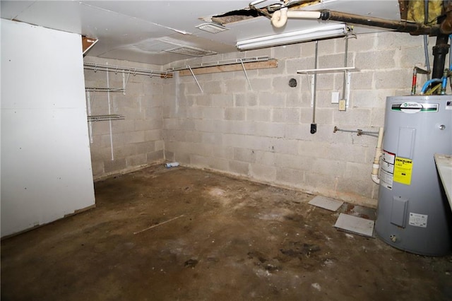 basement featuring concrete block wall, water heater, and visible vents