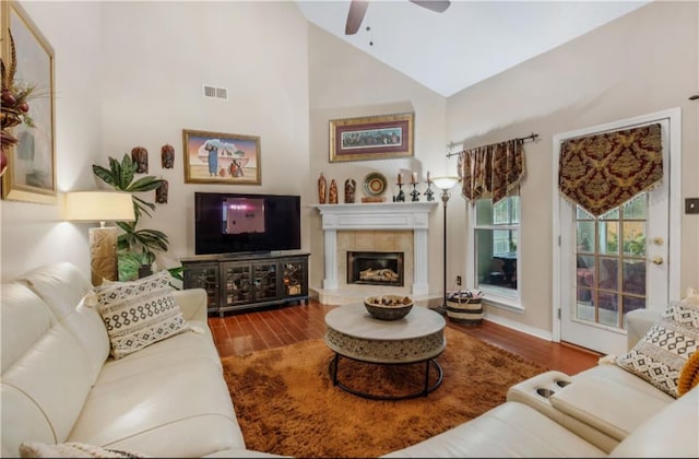 living room featuring hardwood / wood-style flooring, ceiling fan, a tile fireplace, and high vaulted ceiling