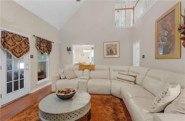 living room with wood-type flooring, a chandelier, and high vaulted ceiling