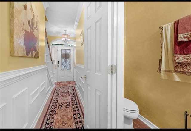 hall with ornamental molding and a chandelier