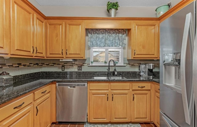 kitchen featuring stainless steel appliances, sink, backsplash, and dark stone countertops