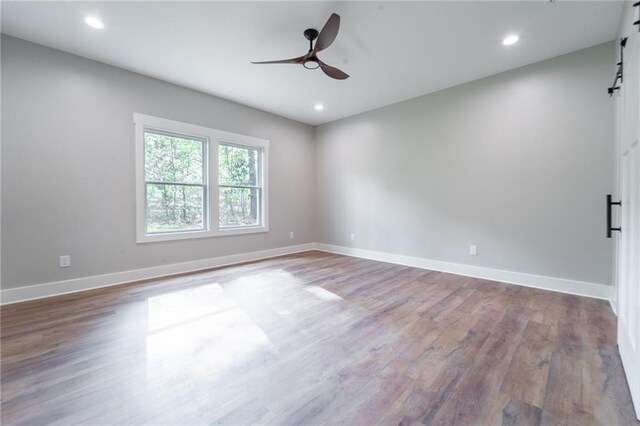empty room with baseboards, a barn door, and ceiling fan