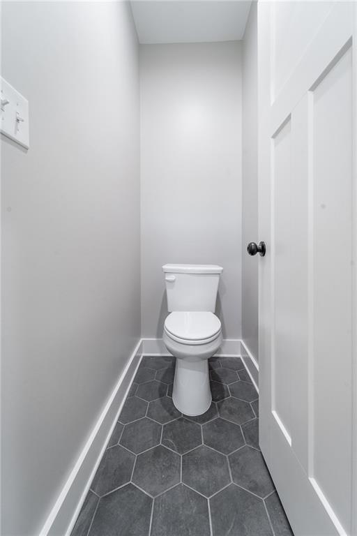 bathroom with baseboards, toilet, and tile patterned flooring