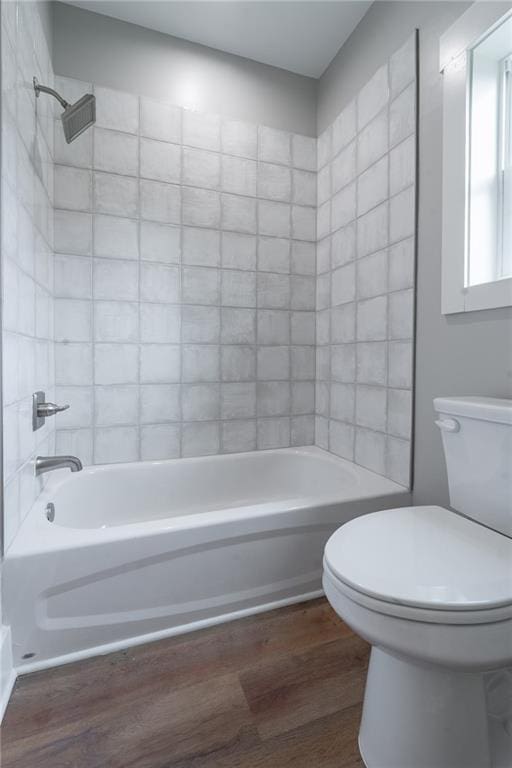 full bath featuring toilet, wood finished floors, and washtub / shower combination