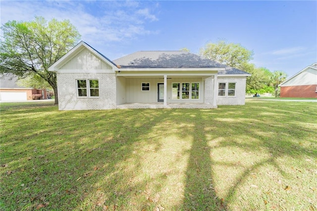 back of house with a patio, brick siding, and a yard