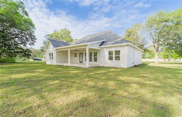 rear view of property featuring ceiling fan, a patio, brick siding, and a yard