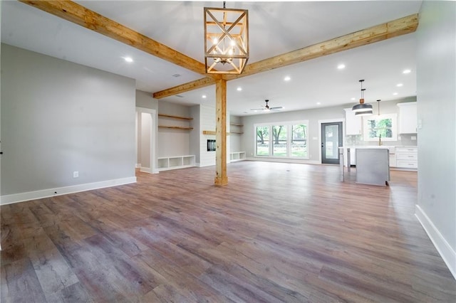 unfurnished living room featuring recessed lighting, baseboards, beamed ceiling, and wood finished floors