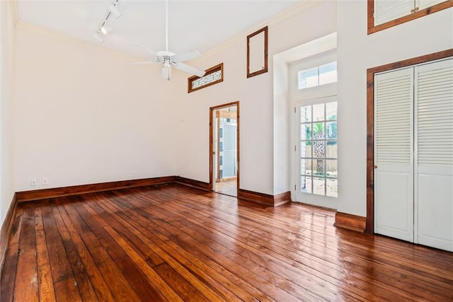 unfurnished room featuring rail lighting, a towering ceiling, ceiling fan, and dark hardwood / wood-style floors