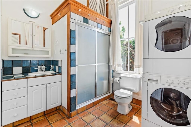 bathroom with tile flooring, large vanity, tasteful backsplash, toilet, and stacked washer / drying machine