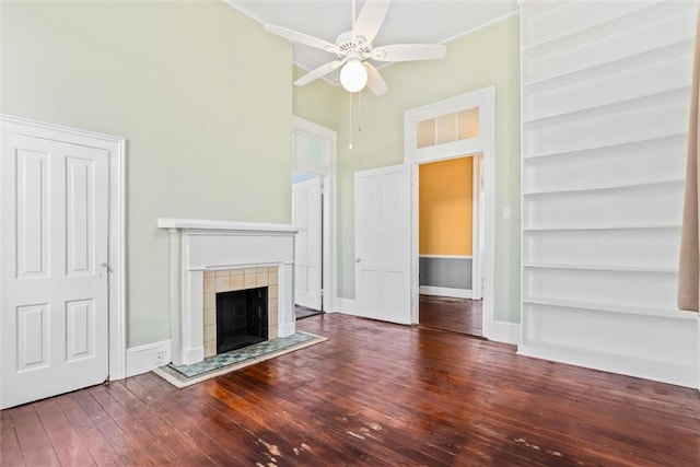 unfurnished living room featuring ceiling fan, dark hardwood / wood-style flooring, a tiled fireplace, and a high ceiling