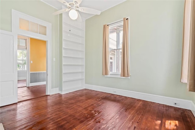 spare room featuring ceiling fan, dark wood-type flooring, and built in shelves