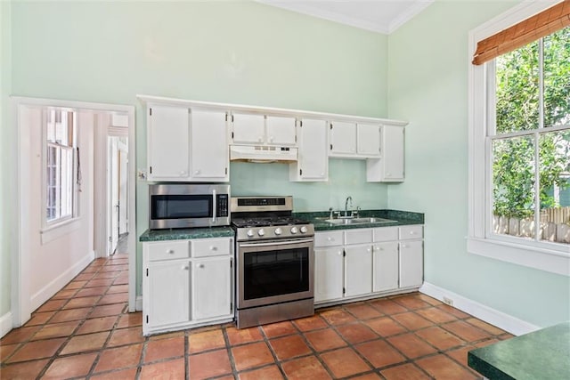 kitchen featuring appliances with stainless steel finishes, crown molding, white cabinets, sink, and tile floors