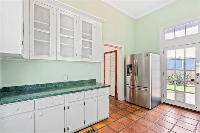 kitchen with white cabinets, light tile flooring, ornamental molding, and stainless steel fridge