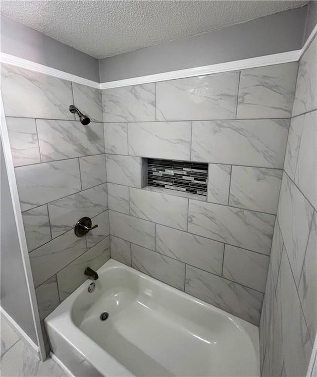 bathroom with tiled shower / bath combo and a textured ceiling