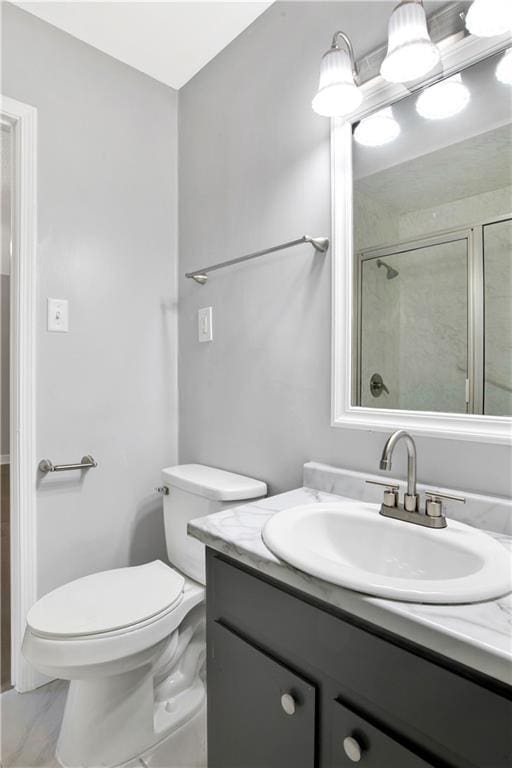 bathroom featuring vanity, a shower with shower door, and toilet