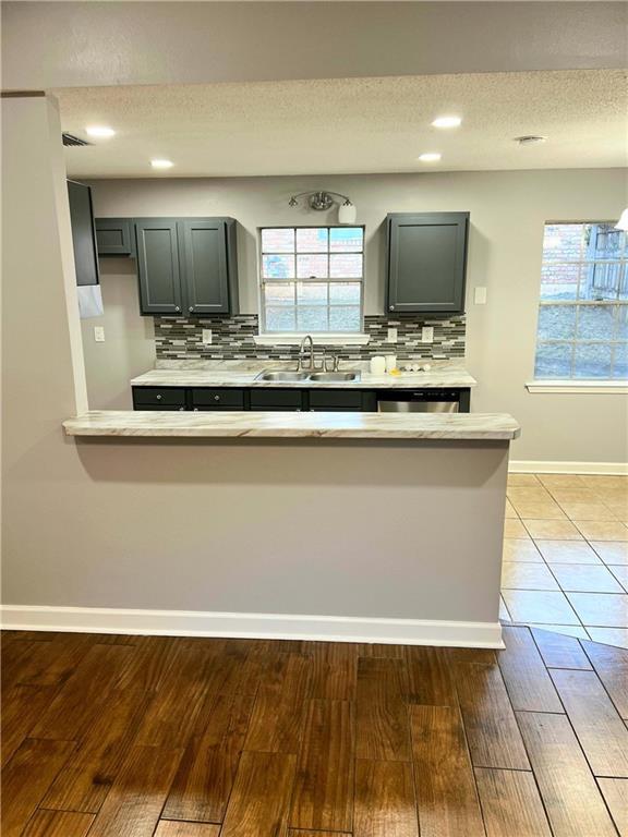 kitchen featuring backsplash, kitchen peninsula, sink, and hardwood / wood-style flooring