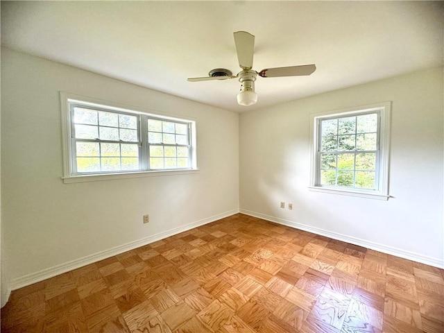 unfurnished room featuring a wealth of natural light, ceiling fan, and baseboards