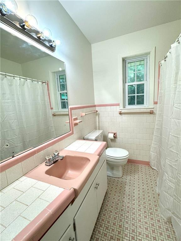 full bathroom with tile walls, a wainscoted wall, vanity, and toilet