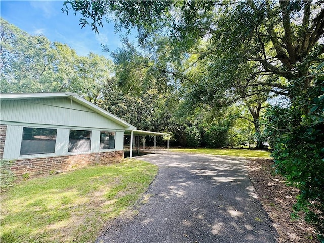 view of home's exterior with a yard, aphalt driveway, and brick siding