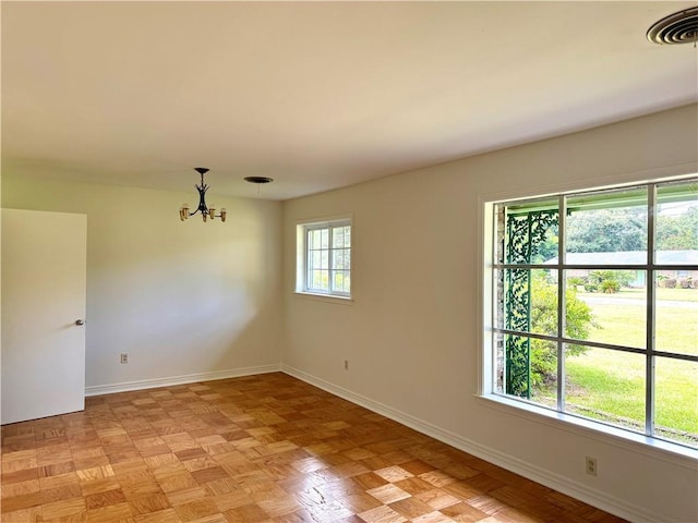 spare room with an inviting chandelier, visible vents, and baseboards