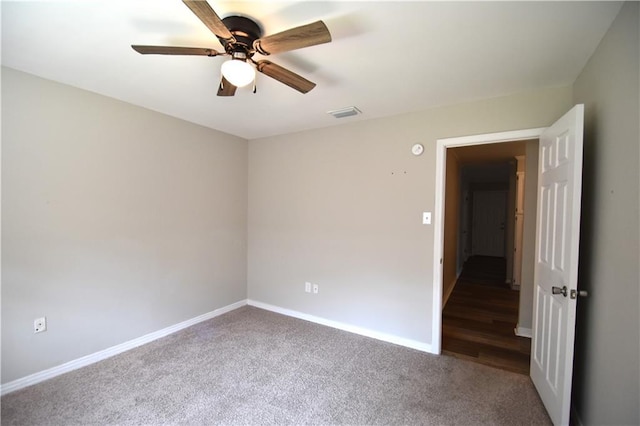 empty room with ceiling fan and dark colored carpet