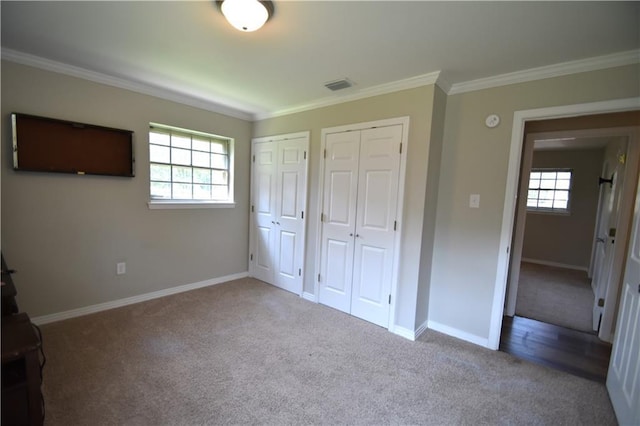 unfurnished bedroom with crown molding, carpet, and two closets