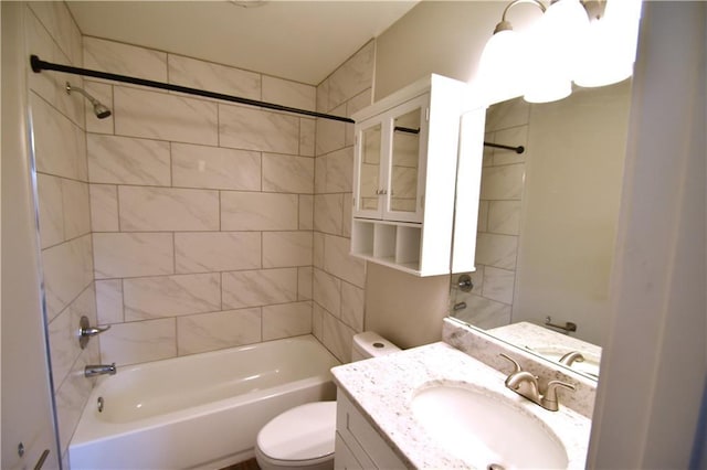 full bathroom featuring vanity, tiled shower / bath combo, and toilet