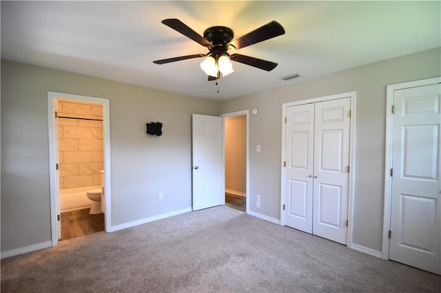 unfurnished bedroom with light carpet, two closets, ensuite bathroom, and ceiling fan