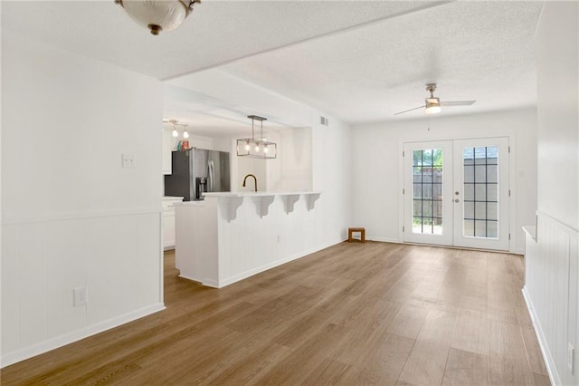 4017 Cottage Hill Rd Unit 17, Mobile, AL 36609 - unfurnished living room with wood finished floors, a ceiling fan, a wainscoted wall, french doors, and a textured ceiling